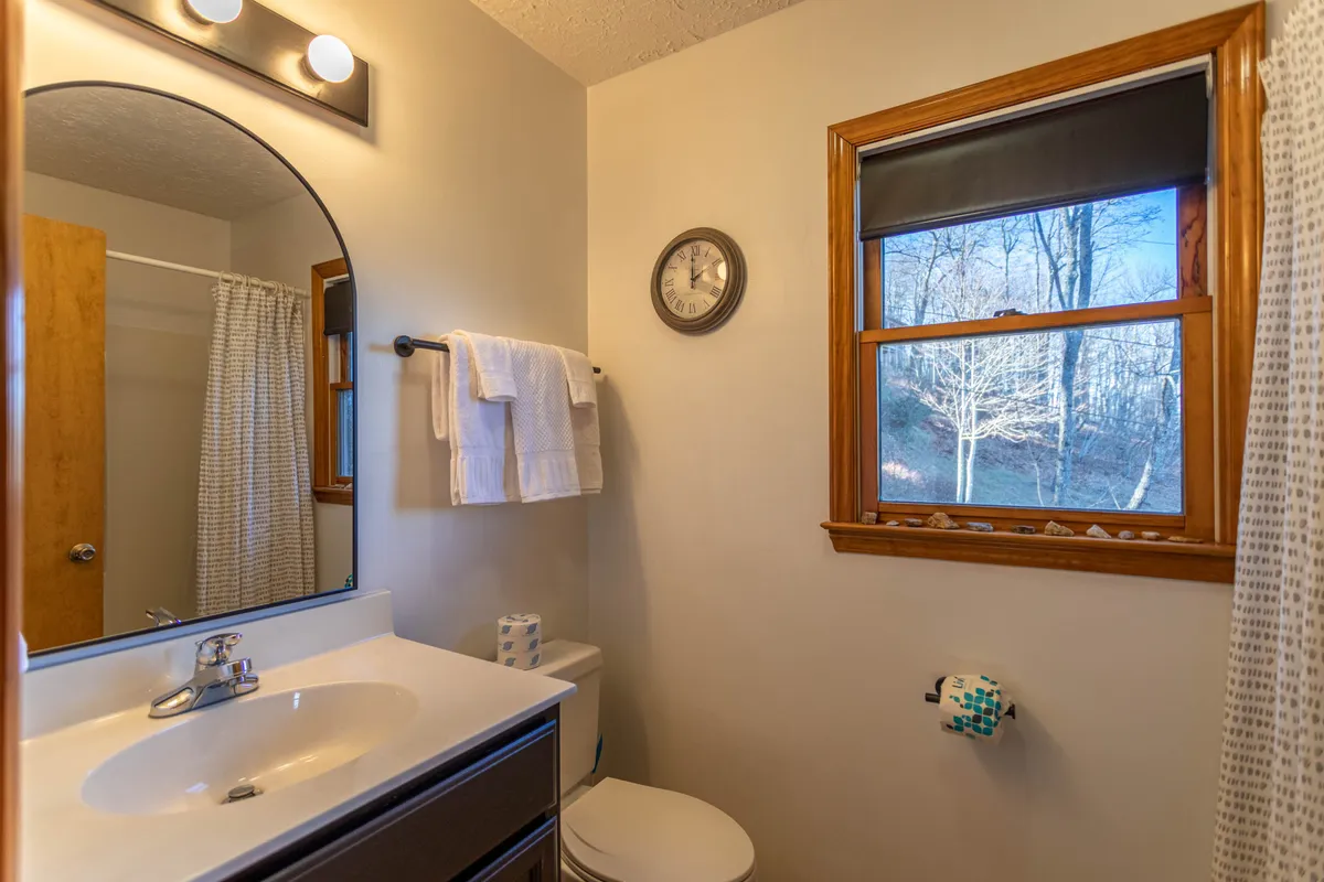 A close-up of a functional interior space featuring a sink, mirror, window, towels, and a clock. This compact area evokes the mudroom/utility area, ideal for freshening up or dropping outdoor gear upon arrival.