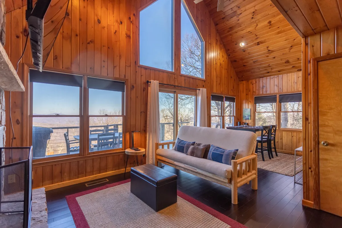 An interior shot capturing a warm entry area with expansive windows, wooden walls, and a comfortable seating area. The space feels welcoming and features a visible transition from outdoors to indoors, aligning with the theme of shedding boots and settling in after arrival.